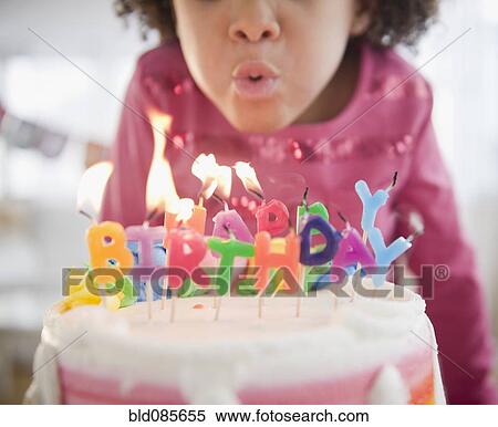 Stock Photography - African American girl blowing out birthday candles. Fotosearch