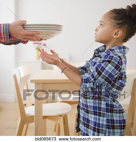 Stock Image - African American girl helping to set table. Fotosearch