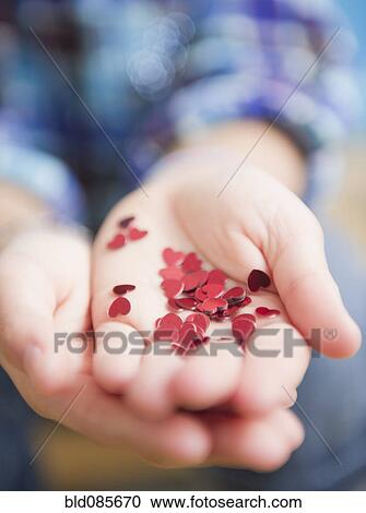 Stock Image - African American girl holding handful of hearts. Fotosearch