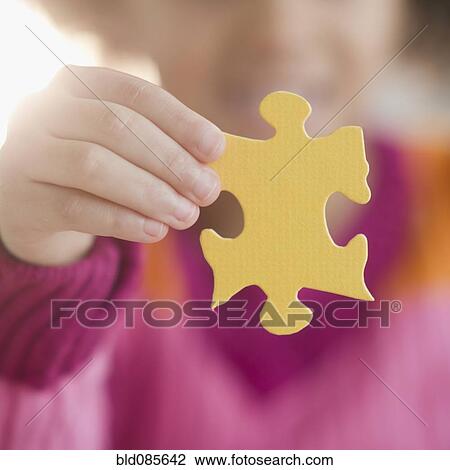 Stock Image - African American girl holding puzzle piece. Fotosearch