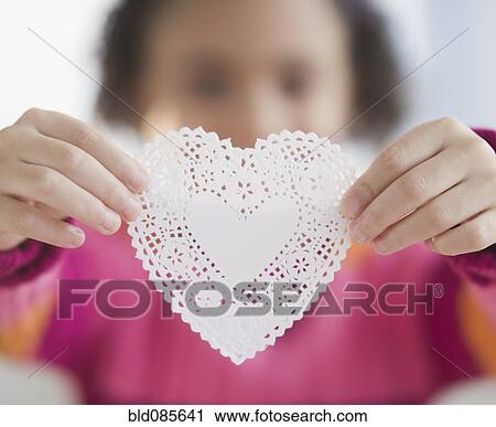 Stock Image - African American girl holding heart-shaped doily. Fotosearch