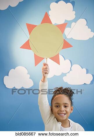 Stock Photo - African American girl holding up paper sun. Fotosearch