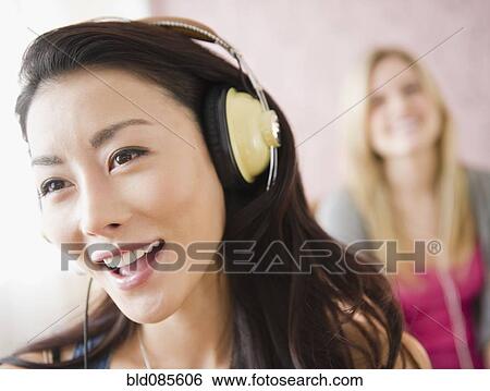 Stock Photograph - Asian woman listening to headphones. Fotosearch