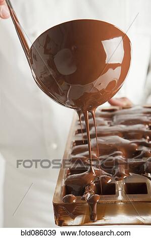 Baker pouring chocolate in mold View Large Photo Image Stock Photo - Baker pouring chocolate in mold. Fotosearch