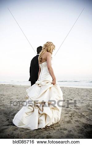 Bride and groom walking on beach View Large Photo Image Stock Photograph - Bride and groom walking on beach. Fotosearch