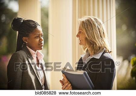 Stock Photo - Businesswomen talking together outdoors. Fotosearch