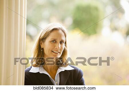 Picture - Caucasian businesswoman leaning against post. Fotosearch