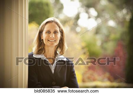 Stock Photography - Caucasian businesswoman leaning against post. Fotosearch