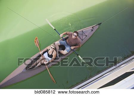 Stock Image - Caucasian couple rowing canoe. Fotosearch