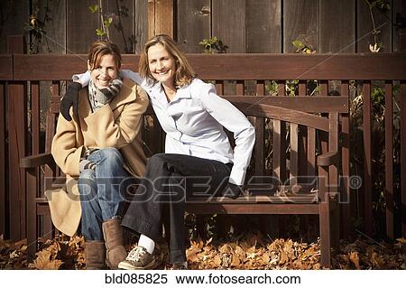 Caucasian friends sitting on bench in autumn View Large Photo Image Stock Photography - Caucasian friends sitting on bench in autumn. Fotosearch