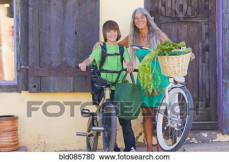 Stock Image - Caucasian grandmother and grandson standing with bicycles. Fotosearch