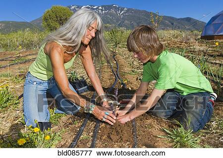 Stock Photo - Caucasian grandmother and grandson working in garden. Fotosearch