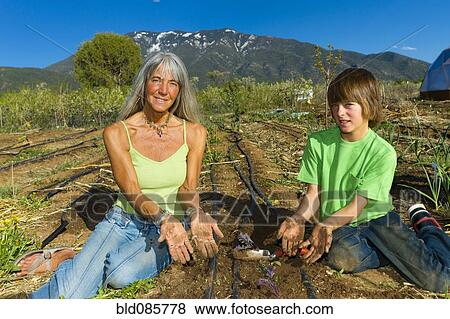 Stock Photo - Caucasian grandmother and grandson working in garden. Fotosearch