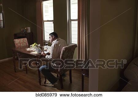 Stock Photo - Caucasian man having dinner and reading. Fotosearch