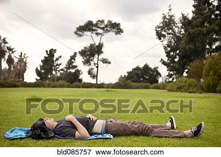 Caucasian man laying in grass in park View Large Photo Image Stock Photo - Caucasian man laying in grass in park. Fotosearch