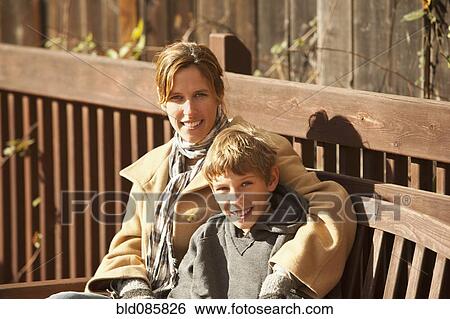 Stock Photograph - Caucasian mother and son sitting on bench. Fotosearch