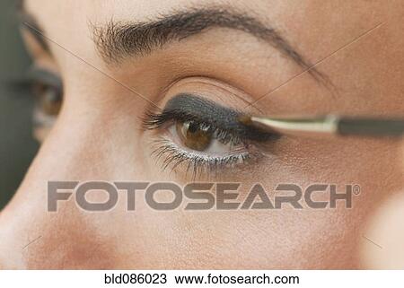 Stock Image - Caucasian woman putting on eyeliner. Fotosearch