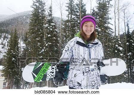 Picture - Chinese snowboarder carrying snowboard. Fotosearch