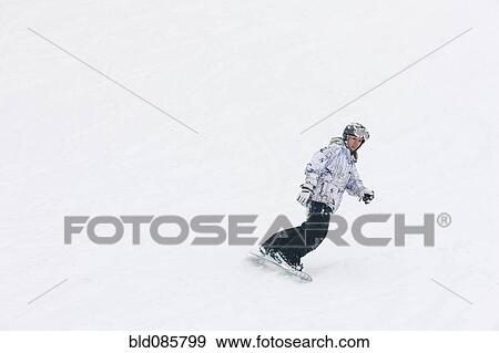 Stock Photo - Chinese snowboarder descending ski slope. Fotosearch