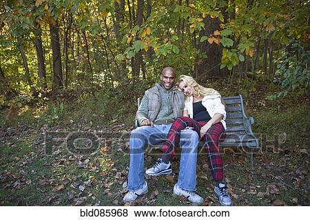 Couple sitting on park bench in autumn View Large Photo Image Stock Photo - Couple sitting on park bench in autumn. Fotosearch