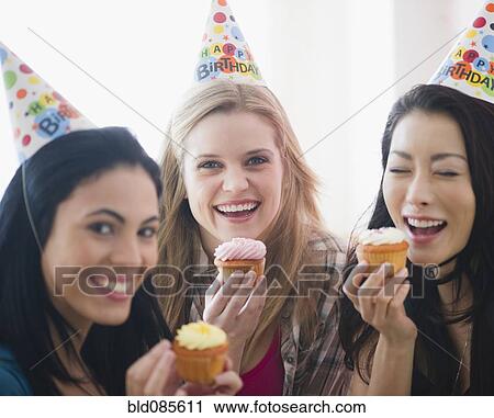 Friends eating cupcakes at birthday party View Large Photo Image Stock Image - Friends eating cupcakes at birthday party. Fotosearch