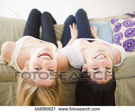 Stock Image - Friends laying on sofa upside-down. Fotosearch