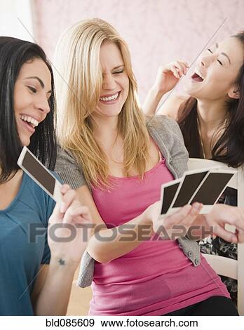 Friends looking at photographs together View Large Photo Image Stock Photo - Friends looking at photographs together. Fotosearch