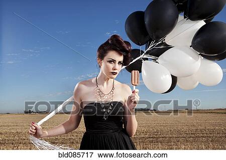 Glamorous woman holding balloons and eating popsicle View Large Photo Image Stock Photo - Glamorous woman holding balloons and eating popsicle. Fotosearch