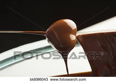 Stock Image - Heart-shaped candy being dipped in chocolate. Fotosearch