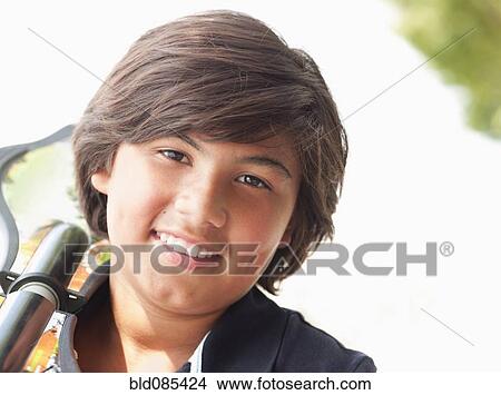 Picture - Hispanic boy carrying skateboard. Fotosearch