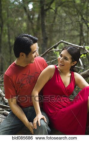 Stock Photograph - Hispanic couple sitting together outdoors. Fotosearch