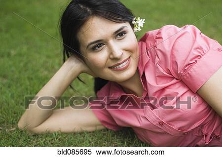 Stock Photography - Hispanic woman laying in grass. Fotosearch