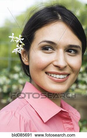 Stock Image - Hispanic woman with flower behind her ear. Fotosearch