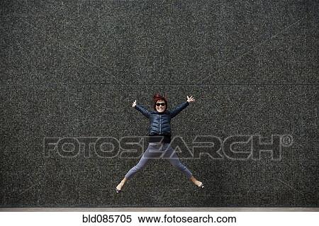 Stock Photography - Korean woman jumping on city sidewalk. Fotosearch