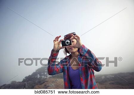 Stock Image - Korean woman taking photograph with digital camera. Fotosearch