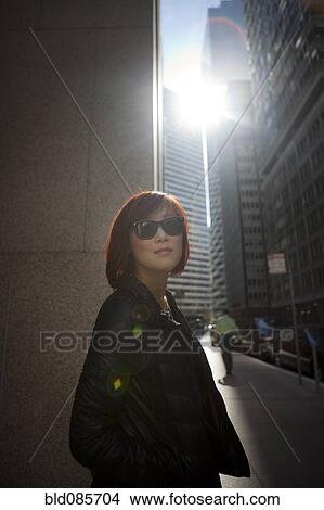 Picture - Korean woman walking on city sidewalk. Fotosearch