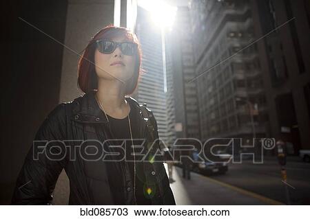 Stock Image - Korean woman walking on city sidewalk. Fotosearch
