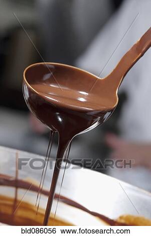 Melted chocolate dripping from ladle View Large Photo Image Stock Photograph - Melted chocolate dripping from ladle. Fotosearch