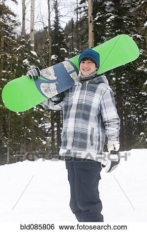 Stock Photograph - Mixed race snowboarder carrying snowboard. Fotosearch