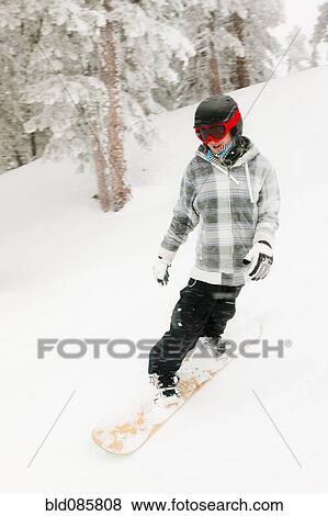 Stock Photo - Mixed race snowboarder descending ski slope. Fotosearch