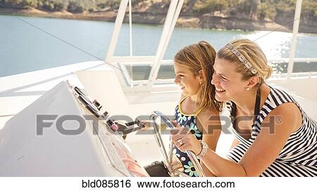 Mother and daughter steering boat on lake View Large Photo Image Stock Photograph - Mother and daughter steering boat on lake. Fotosearch