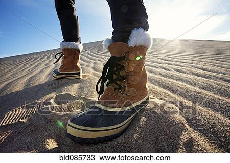 Stock Image - Person wearing boots standing in sand. Fotosearch