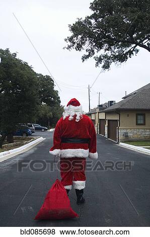 Santa dragging sack down road View Large Photo Image Stock Photo - Santa dragging sack down road. Fotosearch