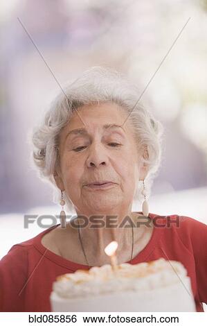 Stock Photograph - Senior Chilean woman blowing out candle on birthday cake. Fotosearch