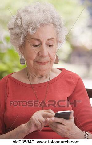 Stock Image - Senior Chilean woman text messaging on cell phone. Fotosearch