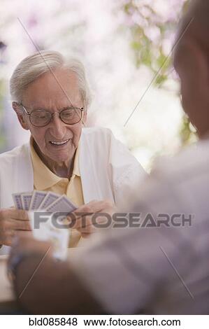 Stock Photo - Senior men playing cards outdoors. Fotosearch