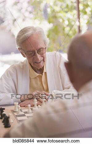 Picture - Senior men playing chess outdoors. Fotosearch