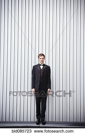 Serious groom standing near wall View Large Photo Image Stock Image - Serious groom standing near wall. Fotosearch