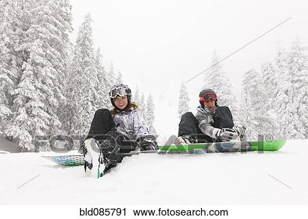Stock Image - Snowboarders sitting in snow. Fotosearch