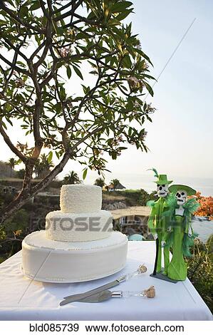 Stock Photo - Wedding cake and Day of the Dead statues on table. Fotosearch